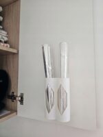 Uchwyt na pionowej płycie przy zawiasie szafki – rolki folii aluminiowej i spożywczej wystają ponad tuby